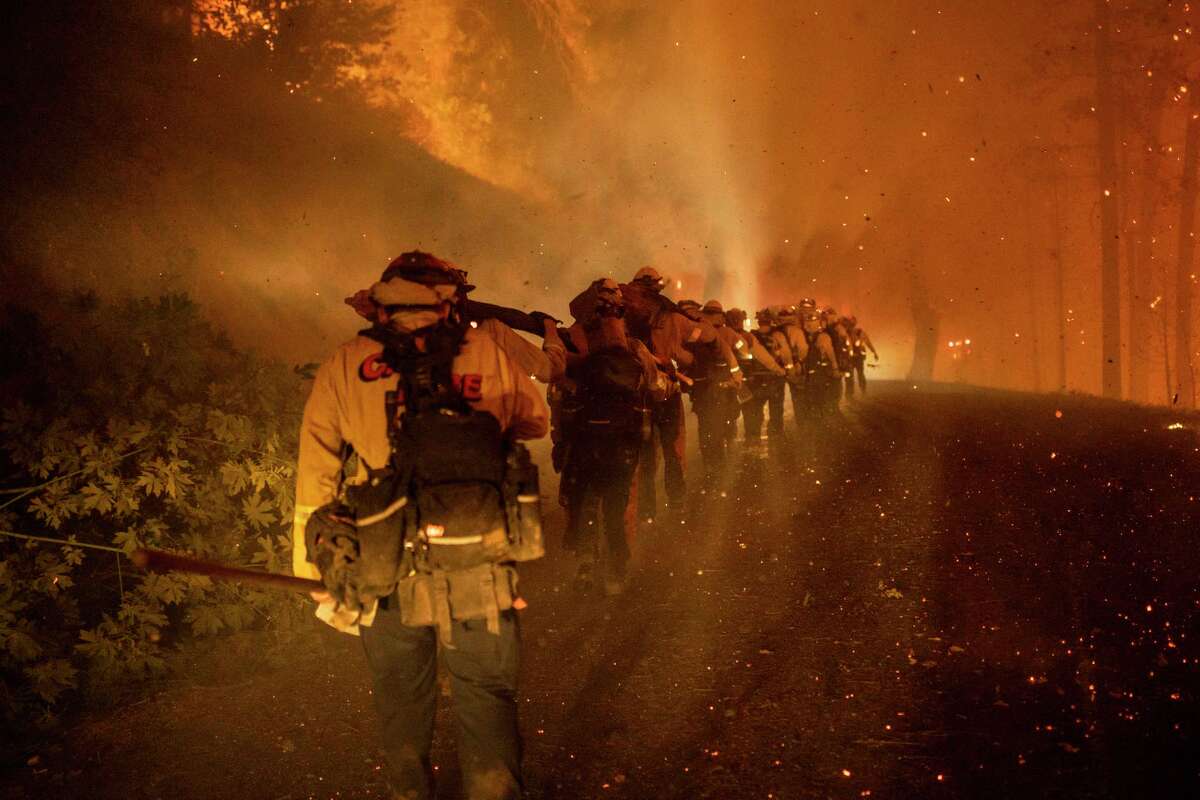 Cal Fire firefighters march through embers along Michigan Bluff road during the Mosquito Fire near Michigan Bluff in unincorporated Placer County, Calif. Wednesday, Sept. 7, 2022.