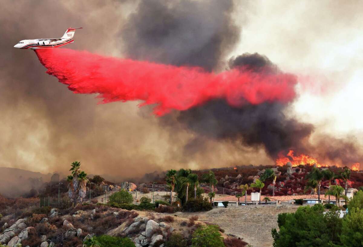HEMET, CALIFORNIA - SEPTEMBER 06: A firefighting aircraft drops fire retardant as the Fairview Fire burns near hillside homes on September 6, 2022 near Hemet, California. The 4,500 acre brush fire has left two dead and forced thousands to evacuate while destroying several homes amid an intense heat wave in Southern California. The National Weather Service issued an Excessive Heat Warning for much of Southern California through September 8. Climate models almost unanimously predict that heat waves will become more intense and frequent as the planet continues to warm.
