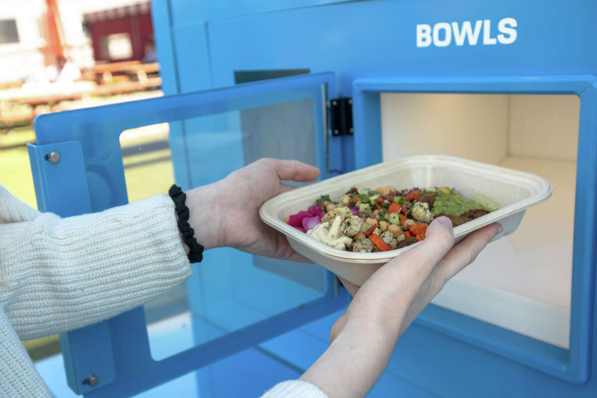 SFGATE reporter Madeline Wells picks up her order at Melzi, an entirely-robot run restaurant at Spark Social San Francisco on Sept. 2, 2022.