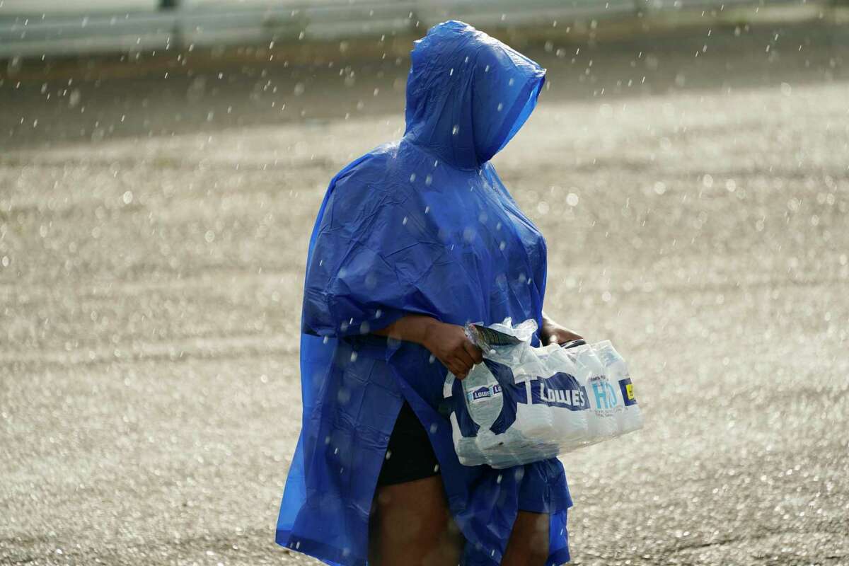 A volunteer carries a case of water in the rain as a coalition of social, fraternal and individuals held a water drive in south Jackson, Miss., in an effort to help residents to deal with the city's long-standing water problems.