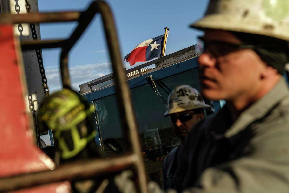 The Texas state flag flies above workers at Latshaw oil drilling rig #43 in the Permian Basin in Odessa, Texas, Wednesday, Oct. 13, 2021. More than 5,000 new well-drilling permits were issued in the Texas portion of the Permian in 2021, as demand for fossil fuels rebounded after a COVID-era slump in demand. Numbers from the first quarter of 2022 show the industry on pace to eclipse that figure. (AP Photo/David Goldman)