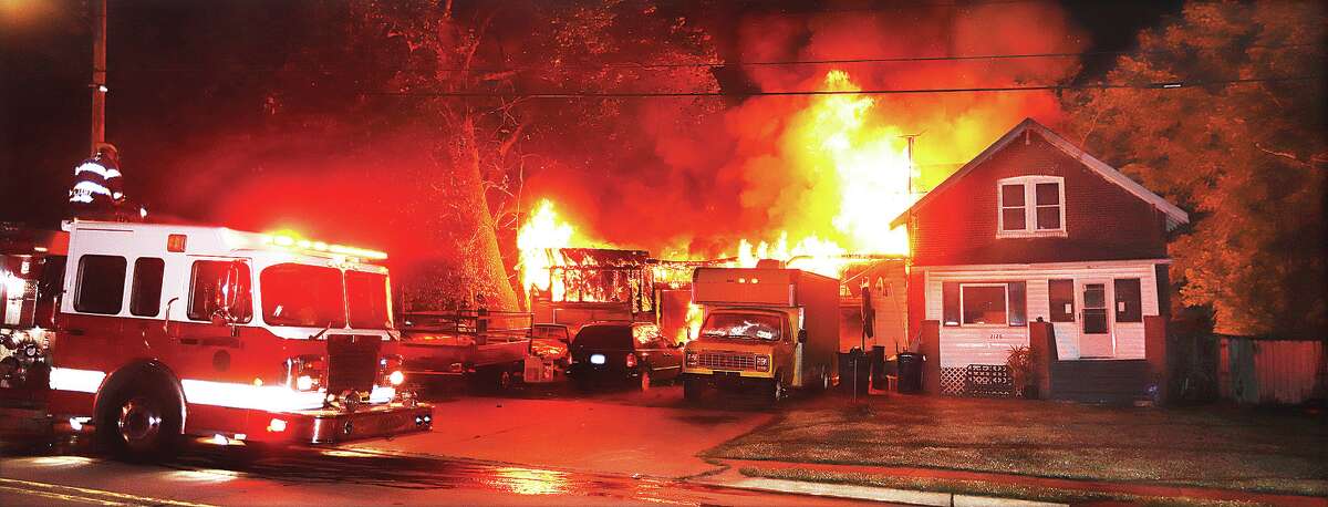 John Badman|The Telegraph Flames burn through a large attached attached garage, left, at a house in the 2100 block of Seminary Street early Friday, spreading to the attic of the house at right.