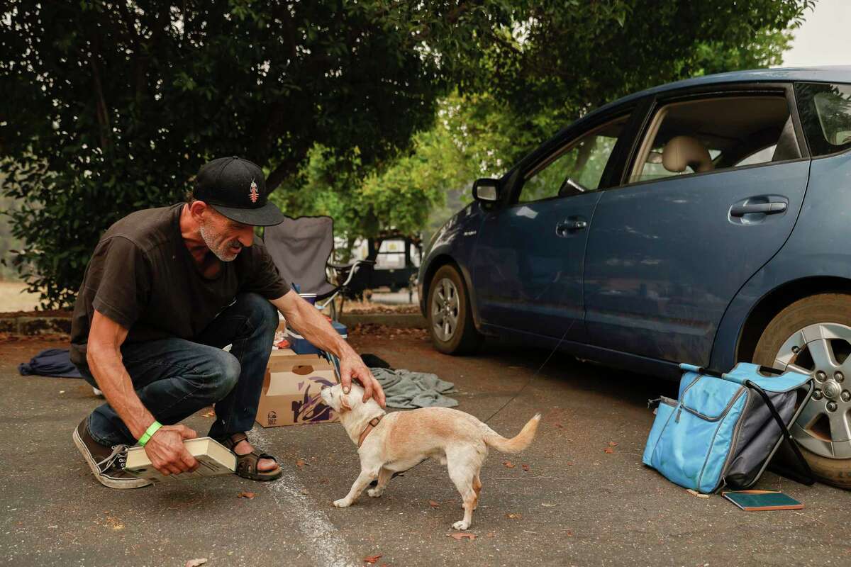 Tim Mull of Michigan Bluff pets his dog Amigo while tidying up his temporary space at an evacuation center at Bell Road Baptist Church in Auburn, Calif. Friday, Sept. 9, 2022 after evacuating from the Mosquito Fire in unincorporated Placer County south of Foresthill.