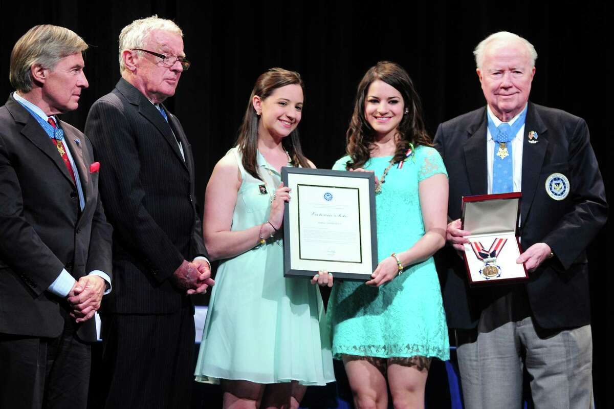 Sisters Jillian (center left) and Carliee Soto (center right) accept the Citizen Honors Medal in honor of their sister, Sandy Hook School teacher Victoria Soto, at a ceremony at Newtown High School on 5/6/2013. Medal of Honor Recipient presenters Paul Bucha (far left) and Thomas Kelley (left) stand with them for a photograph. At right holding the medal is Medal of Honor Recipient presenter Bruce Crandall.