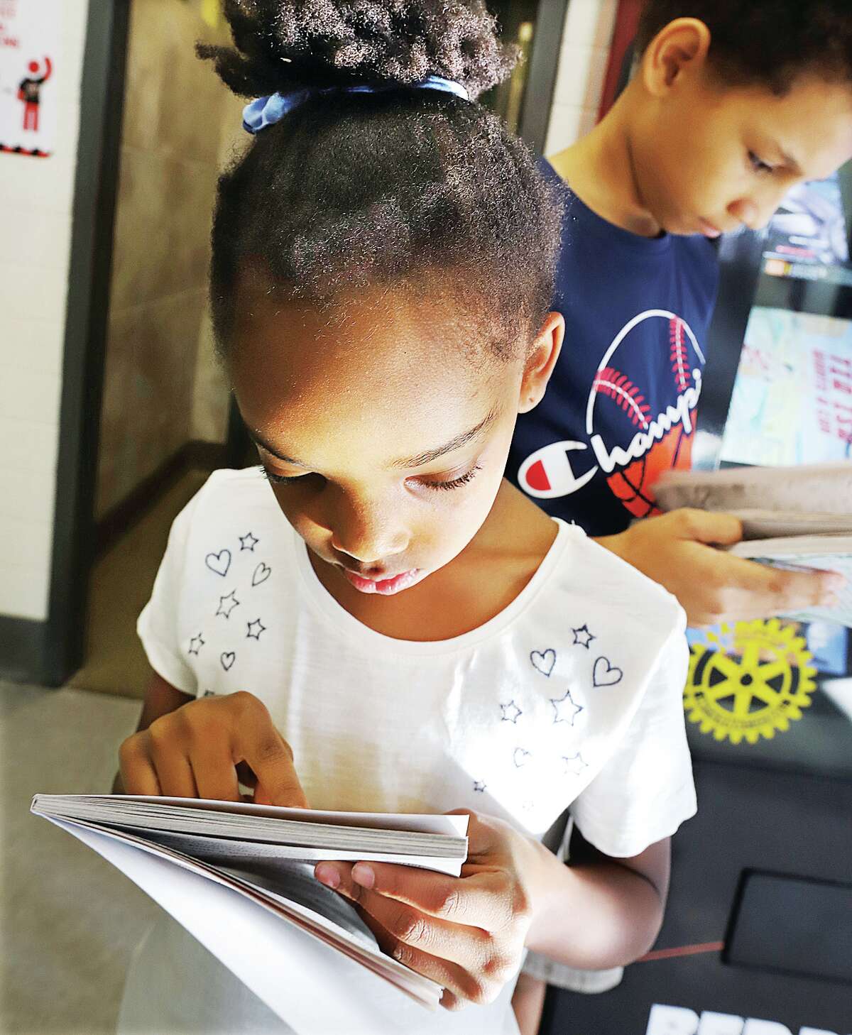 John Badman|The Telegraph North Elementary School fourth grade student Arrissa Johnson, left, and third grader Gavin Gordon, right, began reading their new books as soon as they fell from the new book vending machine.