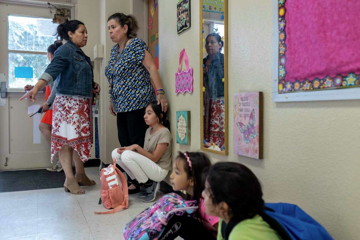 Counselor Elvira Orozco, center, keeps company with students in the hallway during dismissal at Carvajal Elementary School on Sept. 1. The school modified its safety protocols to keep children inside while they wait for parents.