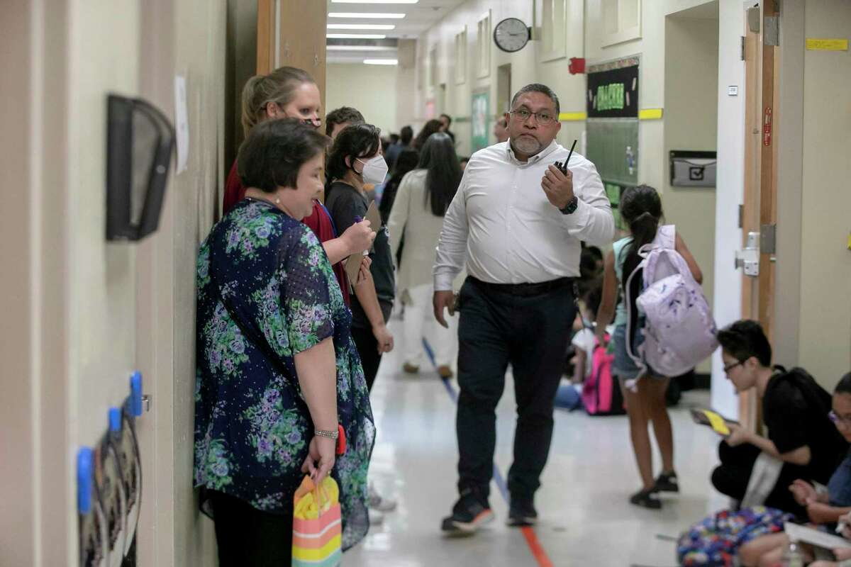 Principal Hugo Saucedo uses a walkie-talkie during dismissal at Carvajal Elementary School on Sept. 1. The school modified its safety protocols to keep children inside while they wait for parents.