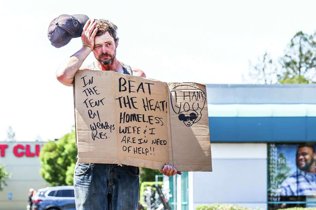 A homeless man named Anthony Fallstead wipes his forehead as he holds a sign that reads “Beat the Heat, Homeless Wife and I are in Need of Help” while panhandling in the scorching heat in Santa Rosa, Calif., on Wednesday, Sept. 7, 2022.