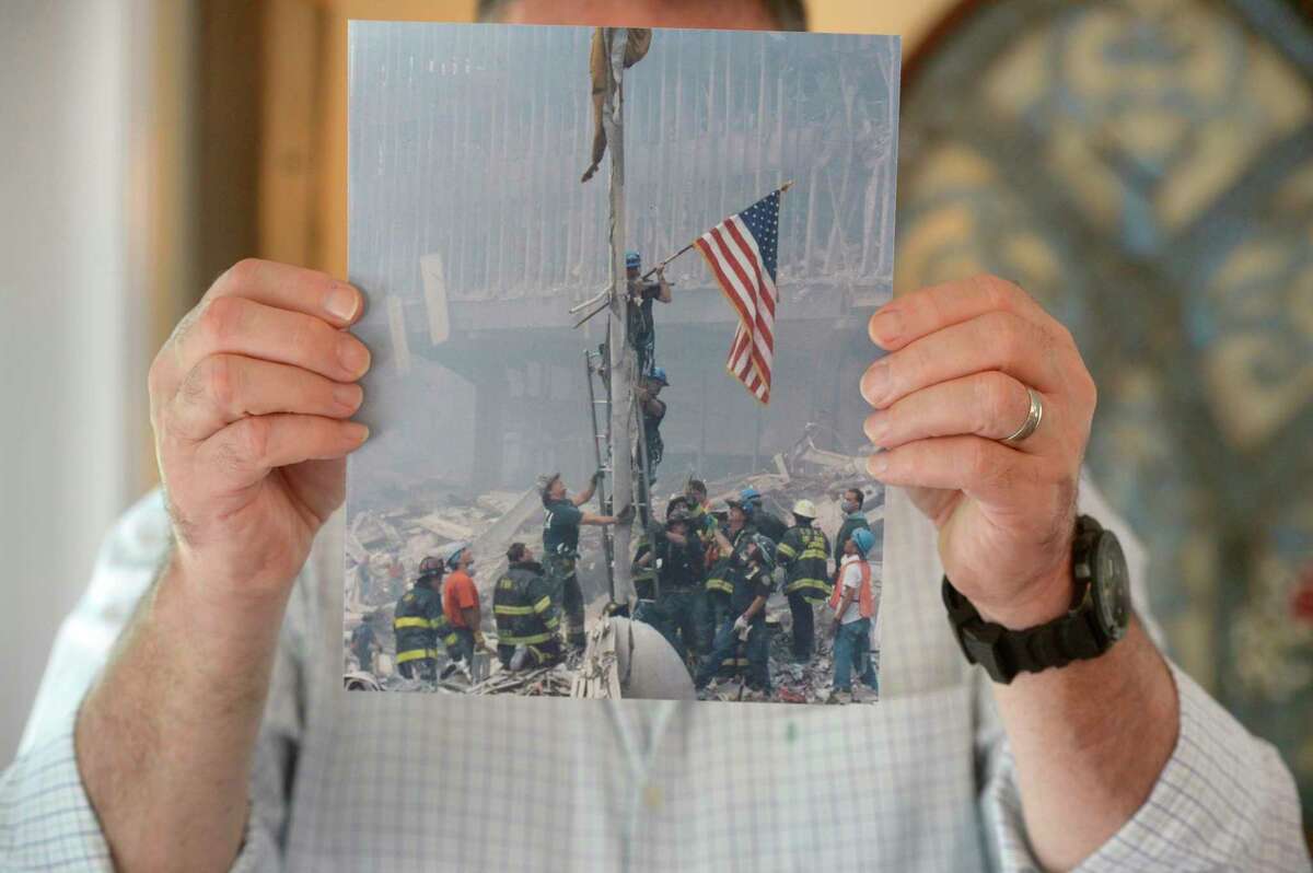 Richard Miller who was with the NYPD’s Emergency Services Unit and is credited with raising the first American flag at the World Trade Center site after the attacks on 9/11 holds a photo of the event. Miller retired as a detective.