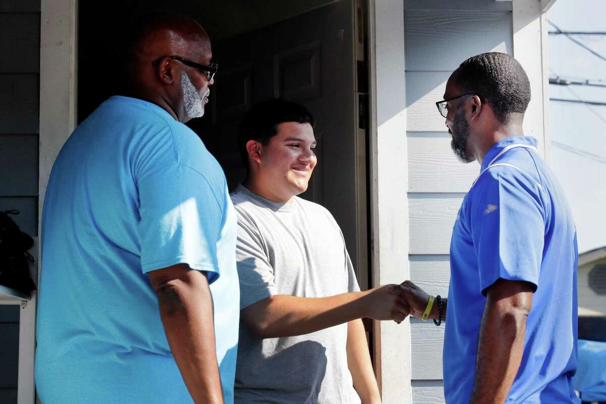 Washington High School student Enrique Alpizar, middle, is met by HISD outreach coordinator Burl Jones, left, and principal Dr. Carlos Phillips, right, as they visit Alpizar’s home to get him back into school as part of the district’s “Grads Within Reach Walk” Saturday, Sept. 10, 2022 in Houston, TX.