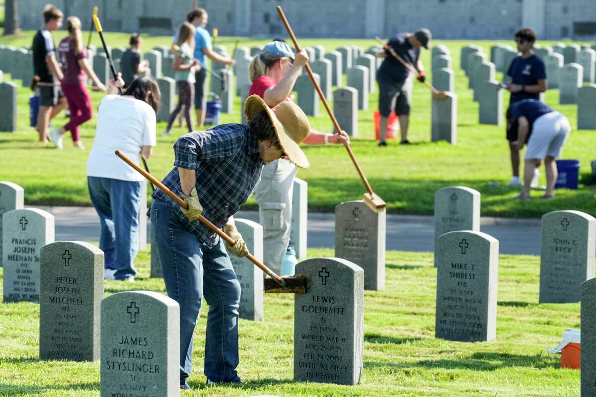 Volunteers scrub a headstone as they help with clean-up and maintenance efforts at Houston National Cemetery Saturday, Sept. 10, 2022 in Houston. The effort, organized by a group called JustServe, is being carried out in observance of 9/11 Day - a federally recognized day created to encourage acts of community service to "rekindle the spirit of unity that arose in America in the immediate aftermath of the terrorist attacks."