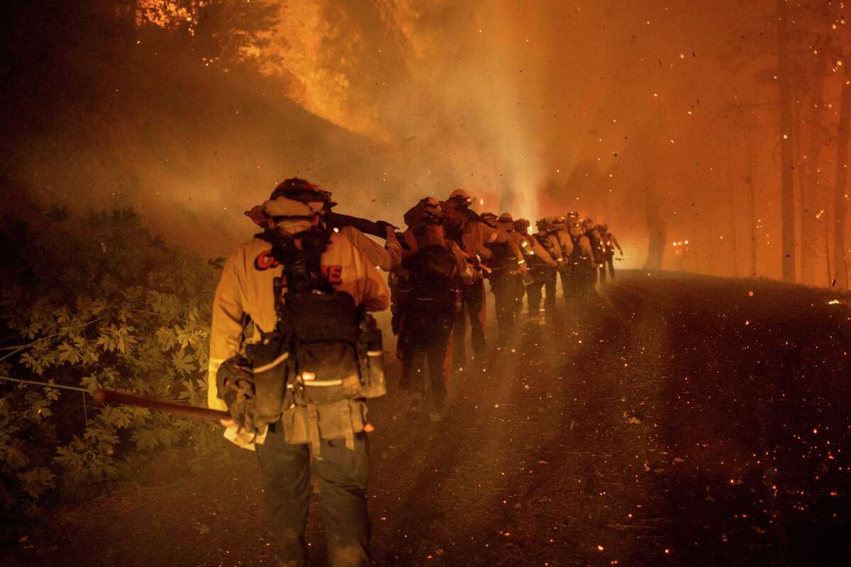 Cal Fire firefighters march through the embers along Michigan Bluff Road during the Mosquito Fire near Michigan Bluff. in unincorporated Placer County, California.  Wednesday, September 7, 2022 (Stephen Lam/San Francisco Chronicle via AP)