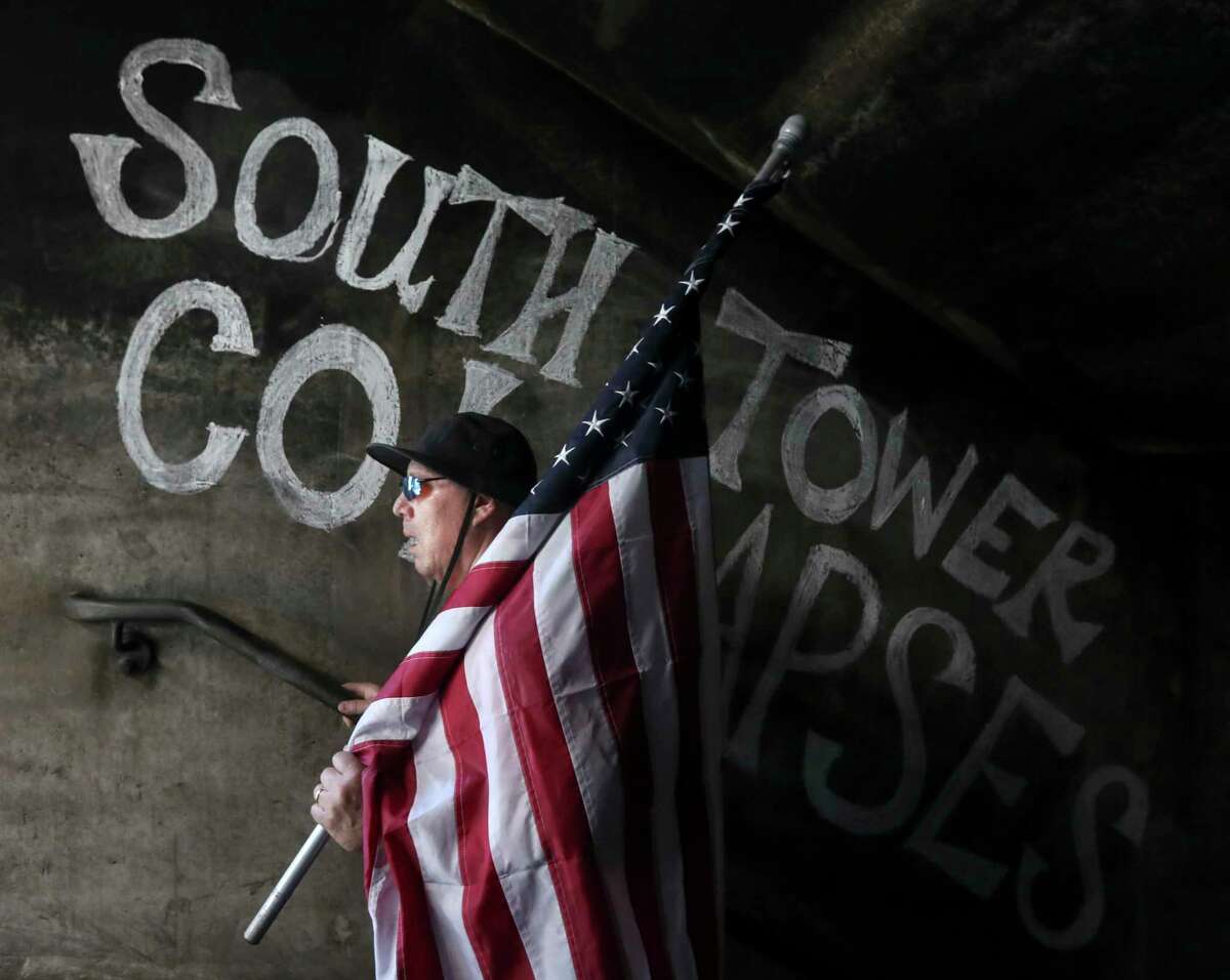 Robert Avila carries an America flag as he walks past a section of wall noting the time the south tower of the World Trade Center fell as firefighters from around Texas take part in a 9/11 memorial climb at the Conroe Fire Training Facility, Saturday, Sept. 10, 2022, in Conroe. Participants climbed 60 flights of stairs to honor the 343 firefighters who died and thousand of emergency workers still affected by the Sept. 11 terrorist attacks on the World Trade Center towers in 2001.