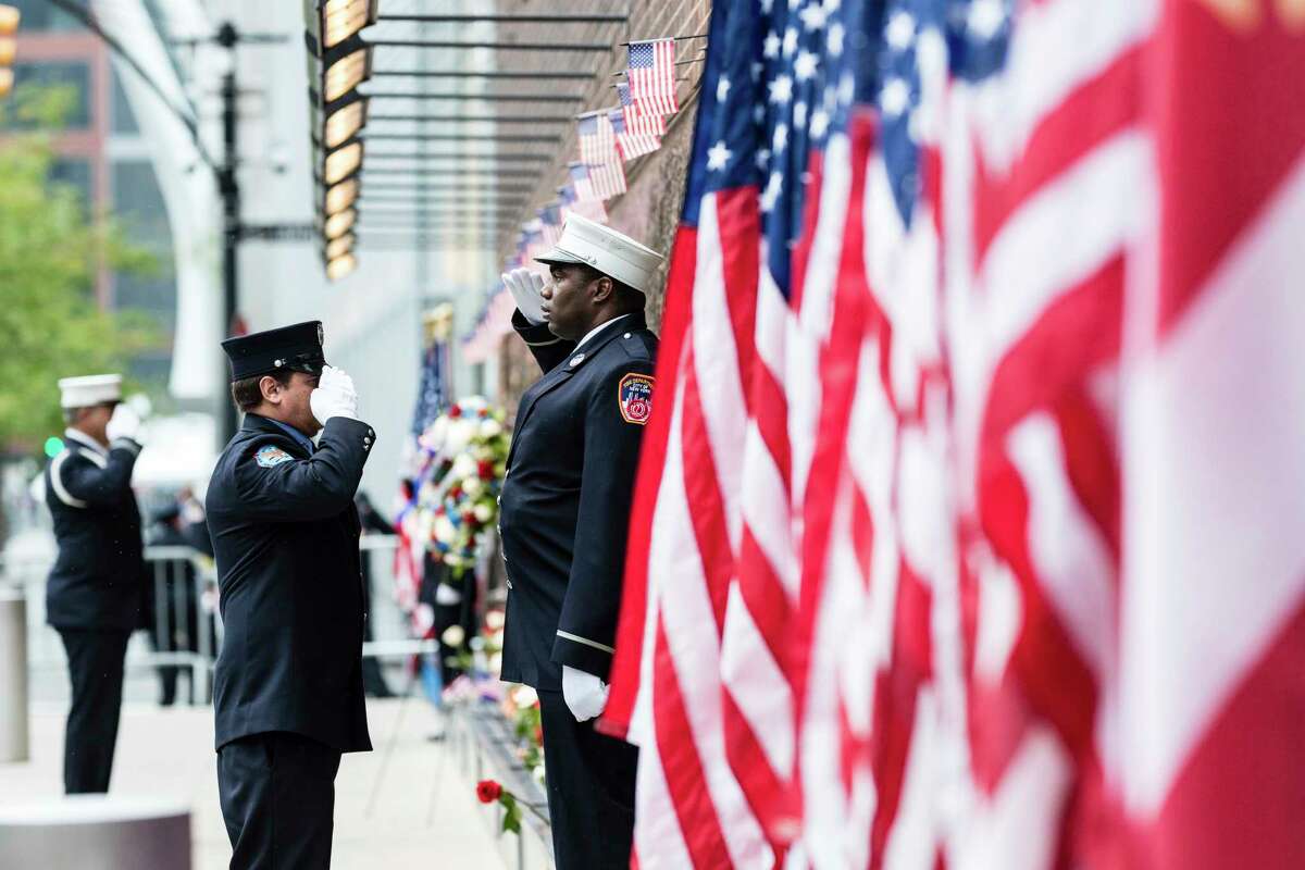 Firefighters salute each other outside the FDNY Engine 10, Ladder 10 fire station near the commemoration ceremony on the 21st anniversary of the September 11, 2001 terror attacks on Sunday, Sept. 11, 2022 in New York.