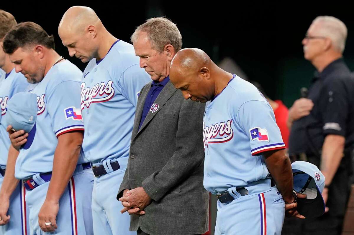 Former President George W. Bush, second from front right, stands with Texas Rangers interim manager Tony Beasley, front right, and others for a moment of silence for 9/11 before a baseball game between the Toronto Blue Jays and the Rangers in Arlington, Texas, Sunday, Sept. 11, 2022.