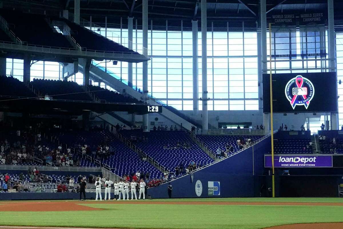 Fans and players take a moment of silence to mark the 9/11 attacks, before the start of a baseball game between the Miami Marlins and the New York Mets, Sunday, Sept. 11, 2022, in Miami.