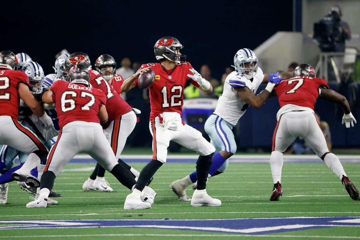 Tampa Bay Buccaneers quarterback Tom Brady (12) prepares to throw a pass as running back Leonard Fournette (7) helps against pressure from Dallas Cowboys linebacker Micah Parsons, second from right, in the second half of a NFL football game in Arlington, Texas, Sunday, Sept. 11, 2022.
