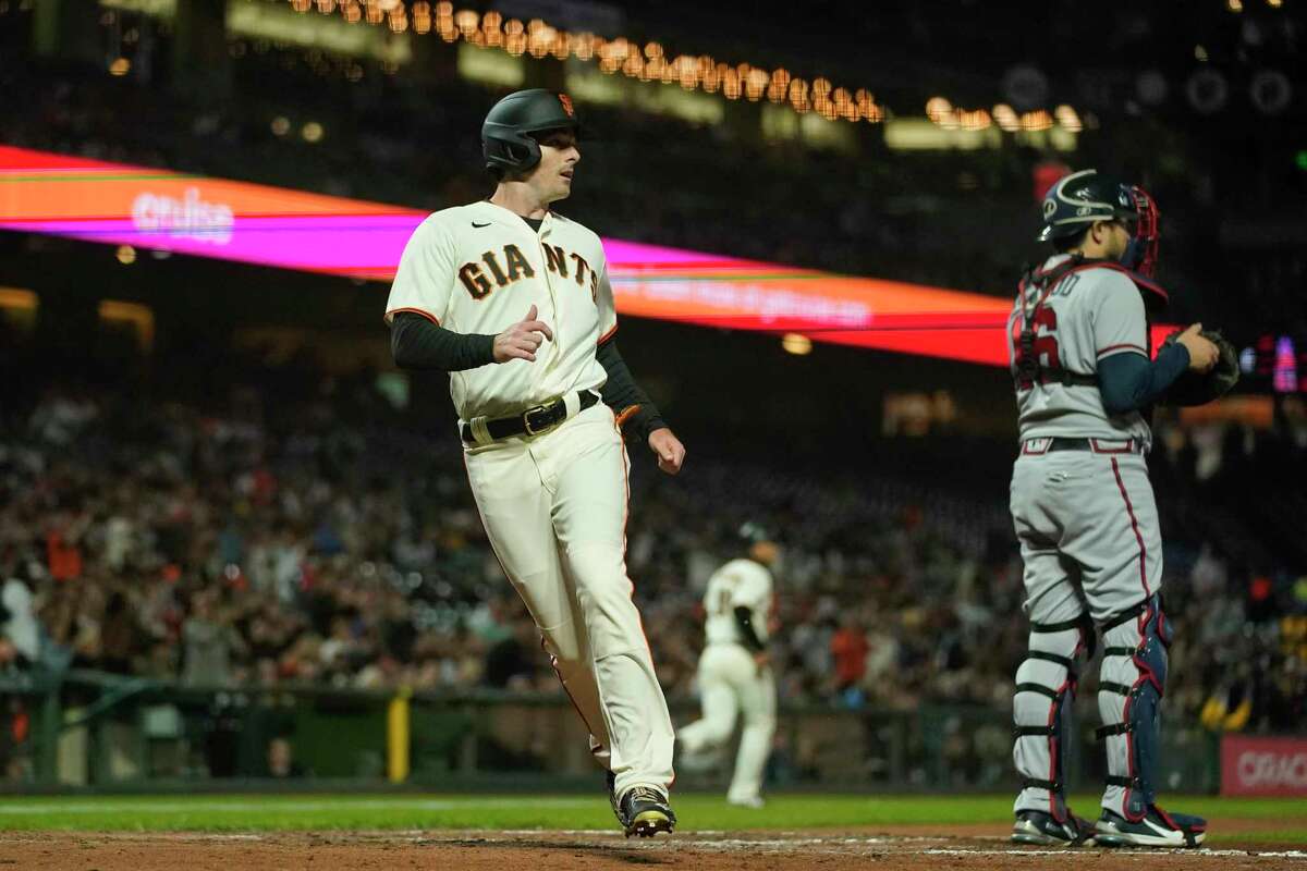 San Francisco Giants' Mike Yastrzemski, left, scores against the Atlanta Braves on a single by Thairo Estrada during the fifth inning of a baseball game in San Francisco, Monday, Sept. 12, 2022. (AP Photo/Godofredo A. Vásquez)