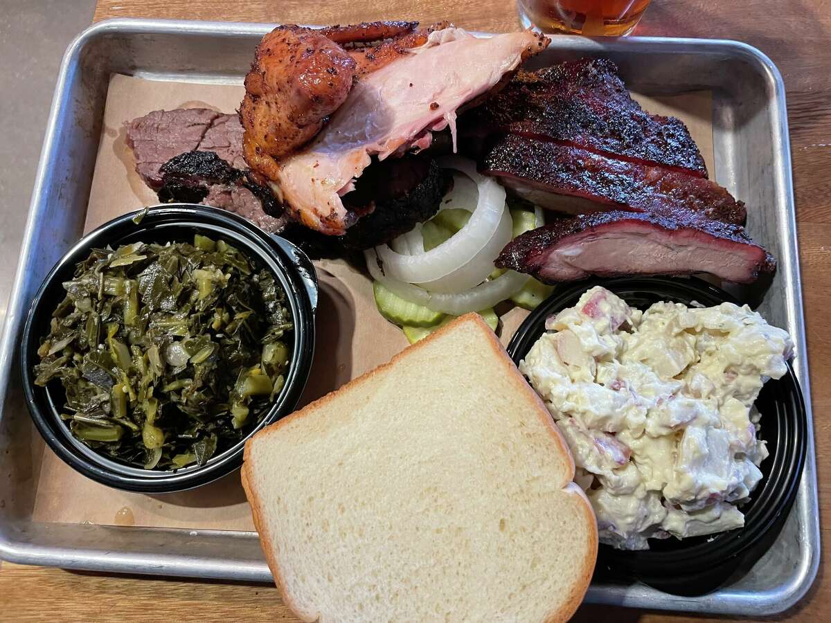 A True Texas BBQ platter is served with collard greens, potato salad, pork ribs, chicken and brisket.