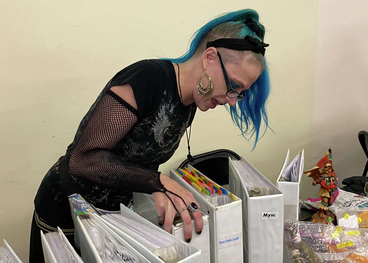 Amber Furtah, a Wiccan who sold witchcraft-related items at the Bad Axe Psychic Fair on Sept. 10, thumbs through the volumes of a spiritual and witchcraft compendium she assembled herself.