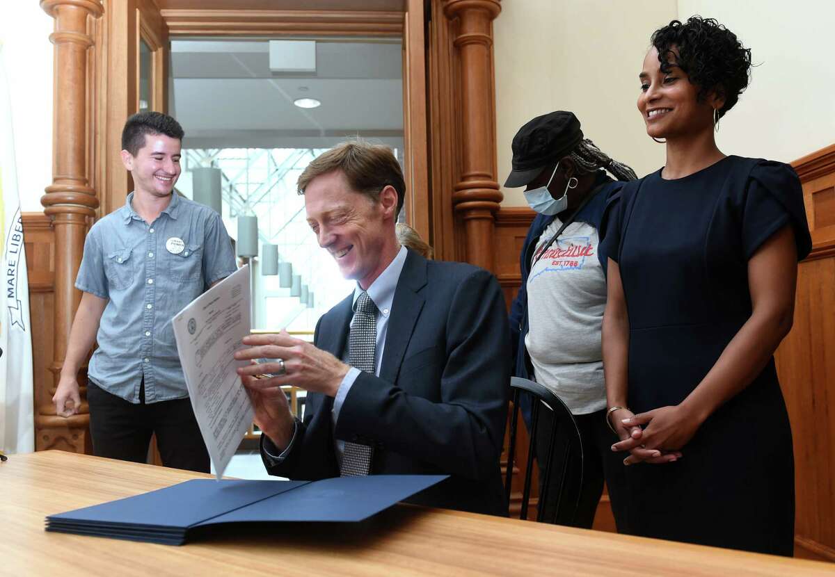 New Haven Mayor Justin Elicker, seated, prepares to sign a tenants union ordinance at City Hall in New Haven on September 13, 2022. From left are tenant organizer Luke Melonakos-Harris, Elicker, Quinnipiac Gardens Tenant Union member Jackie Sewell-Freelove and Fair Rent Commission Executive Director Wildaliz Bermudez.
