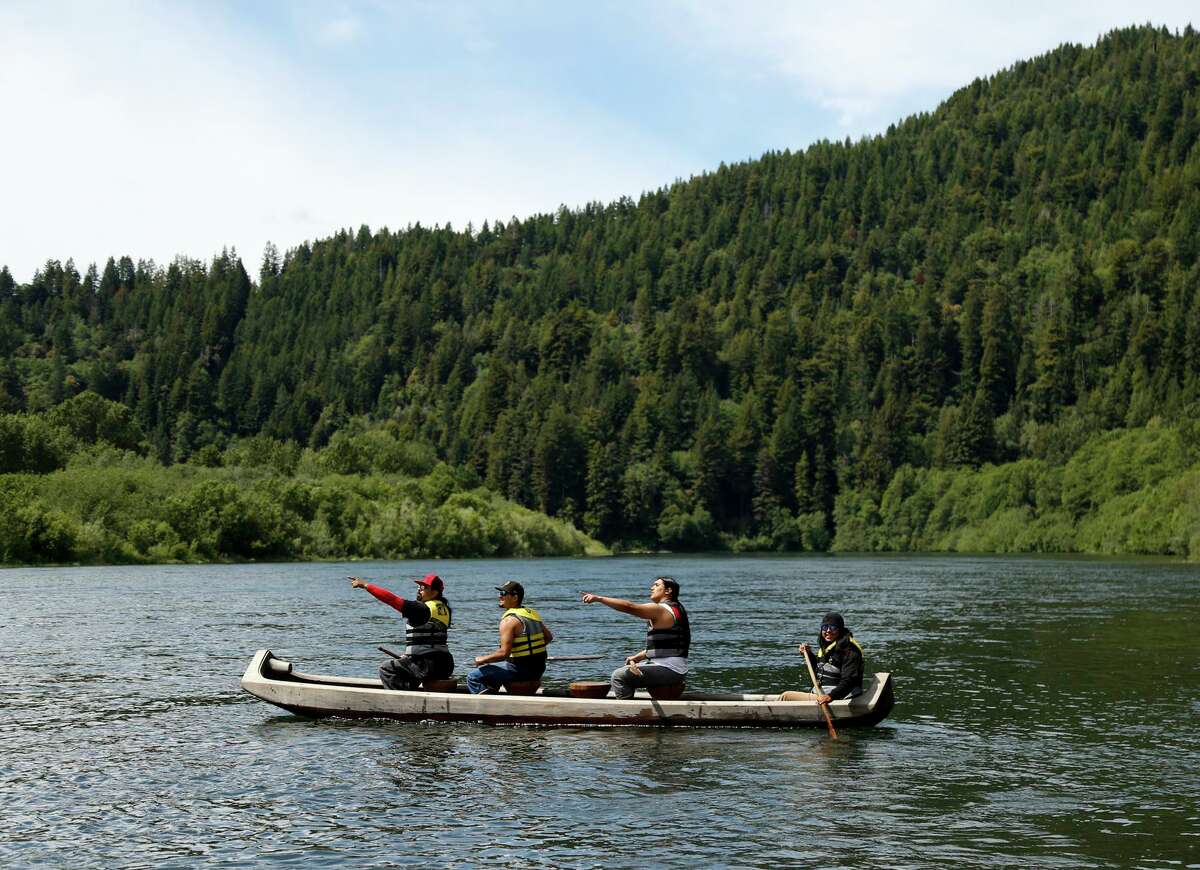 Yurok tribal members Walker Gensaw (front) and Kobe Mitchell paddle a traditionally made redwood canoe on the Klamath River. The Yurok has recently begun offering canoe tours on the river.