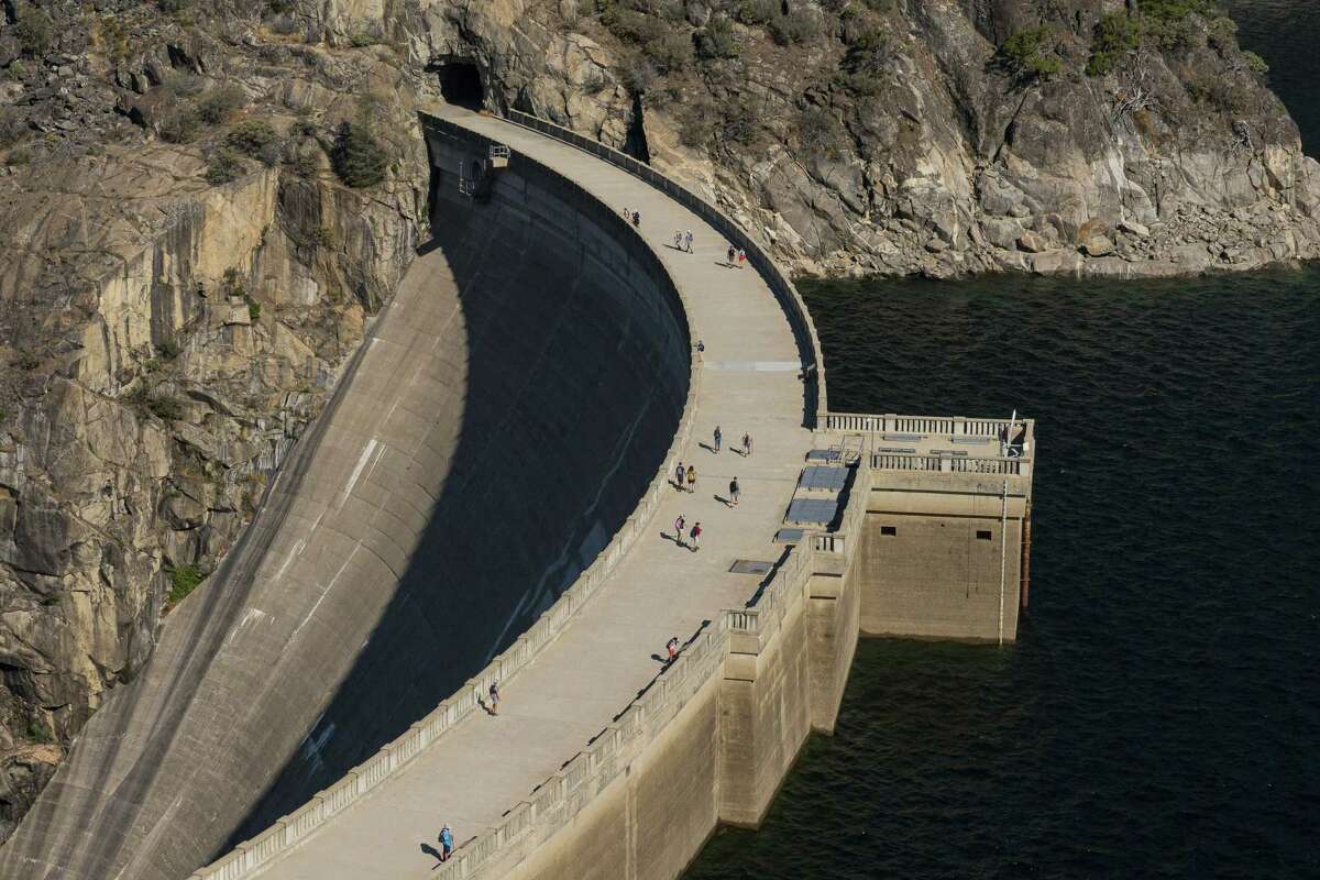 Park visitors walk across O'Shaughnessy Dam in Yosemite National Park, Calif., on September 1, 2022. The O?•Shaughnessy Dam was completed in 1938 and is 430-feet tall. The 117-billion-gallon Hetch Hetchy reservoir supplies drinking water to about 2.5 million San Francisco Bay Area residents and hydro-electric power generated by two plants downstream.