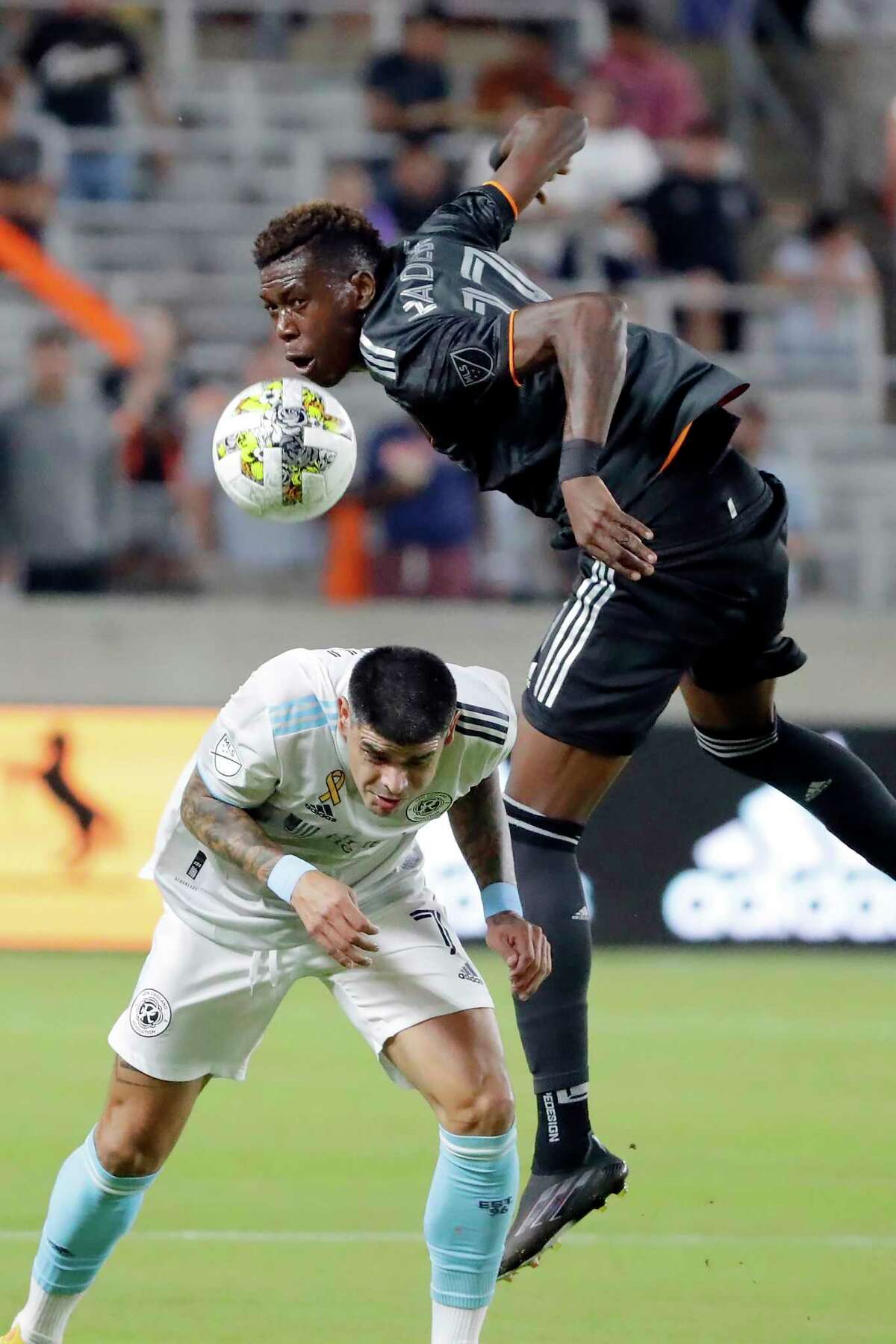 Houston Dynamo defender Teenage Hadebe, top, heads the ball over New England Revolution forward Gustavo Bou during the first half of an MLS soccer match Tuesday, Sept. 13, 2022, in Houston. (AP Photo/Michael Wyke)