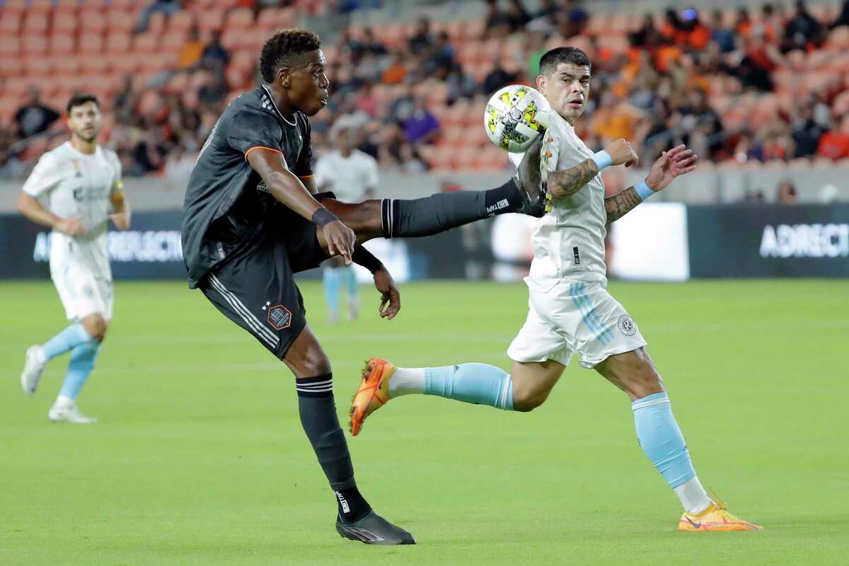 Houston Dynamo defender Teenage Hadebe, left, kicks away the ball next to New England Revolution forward Gustavo Bou, right, during the first half of an MLS soccer match Tuesday, Sept. 13, 2022, in Houston. (AP Photo/Michael Wyke)