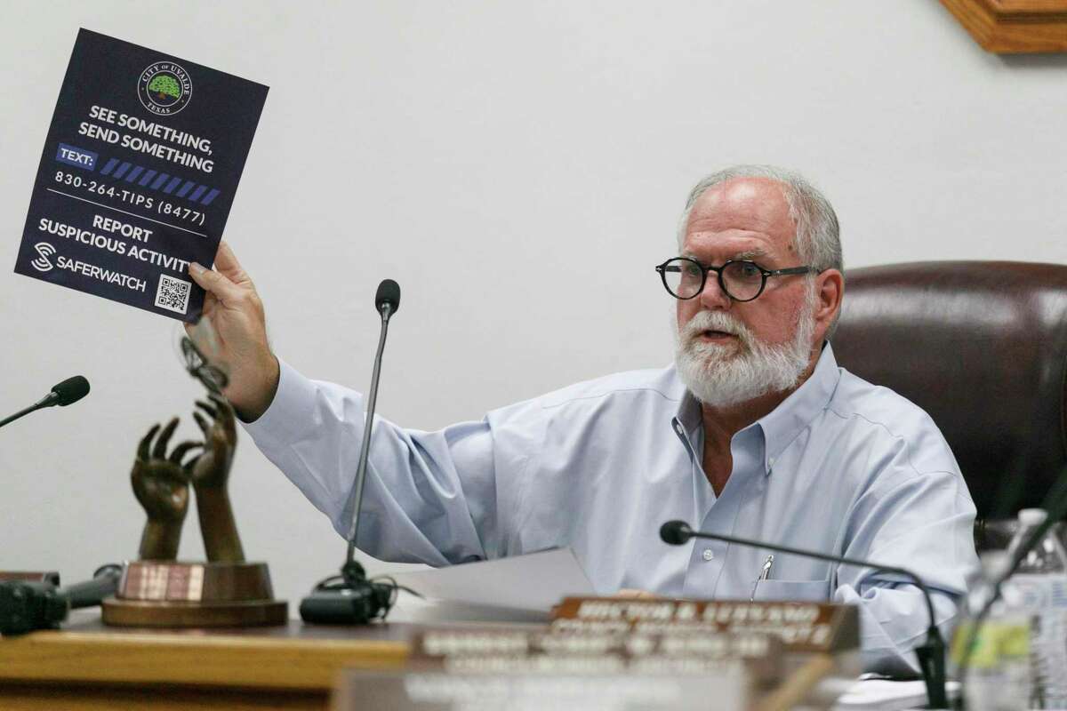 Uvalde Mayor Donald McLaughlin Jr. holds up a flyer advertising a tip line for residents to call to report anything suspicious.