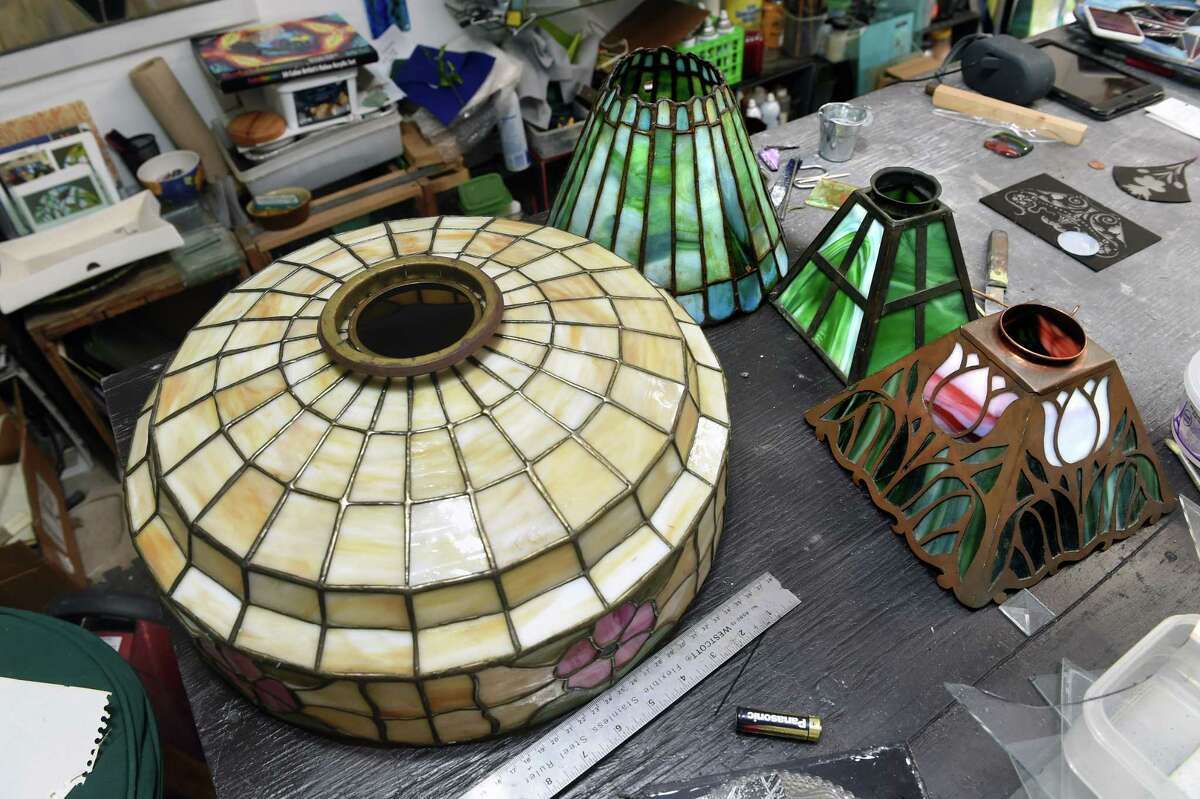 Stained glass lampshades await repair by Jayne Crowley of J.C. ArtGlass Designs at her studio in Branford.