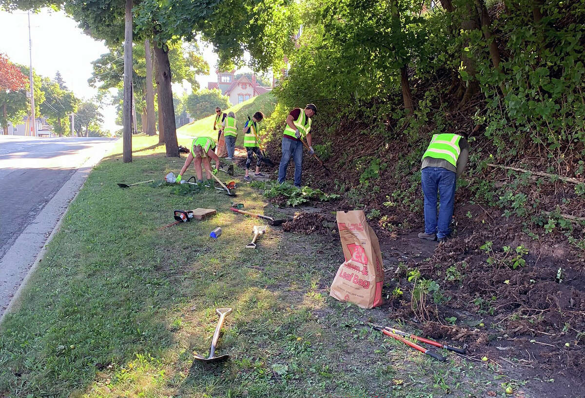 Members of the Manistee Neighborhood Restoration and Beautification Commission and volunteers work on a retaining wall at First Street in Manistee during a community service day on Saturday. 