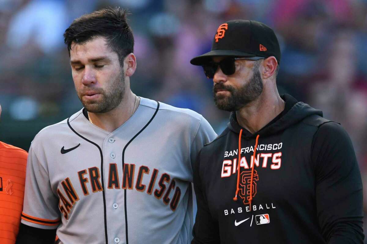 San Francisco Giants' Austin Wynns, left, is accompanied by manager Gabe Kapler as he walks off the field after being hit by a pitch during the sixth inning of the team's baseball game against the Chicago Cubs on Friday, Sept. 9, 2022, in Chicago. Chicago won 4-2. (AP Photo/Paul Beaty)