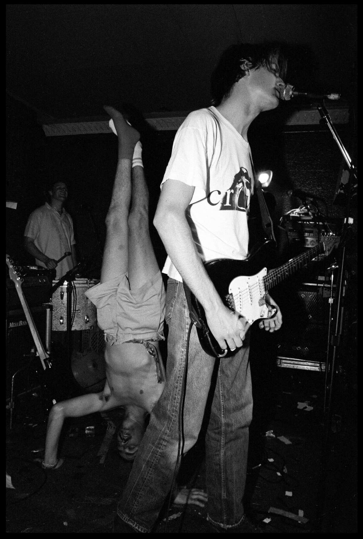 Stephen Malmus and Gary Young, standing on their heads, performing on stage in the early 1990s. 