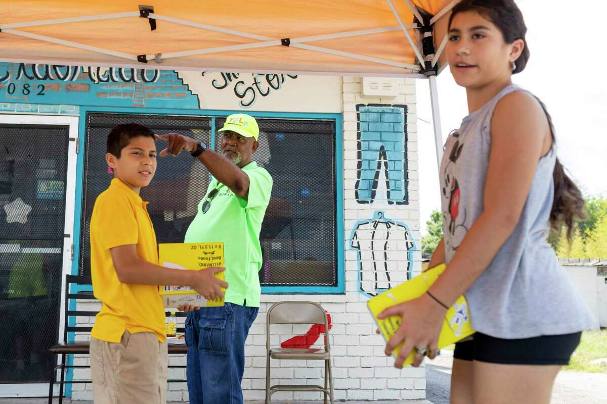 Dan McIrven directs young volunteers Jose Soto, 12, and Jaelyssa “Chilli” Soto, also 12, to vehicles that arrived to recive food outside Treasures of Eldorado Thrift in San Antonio, TX, on Sept. 13, 2022.
