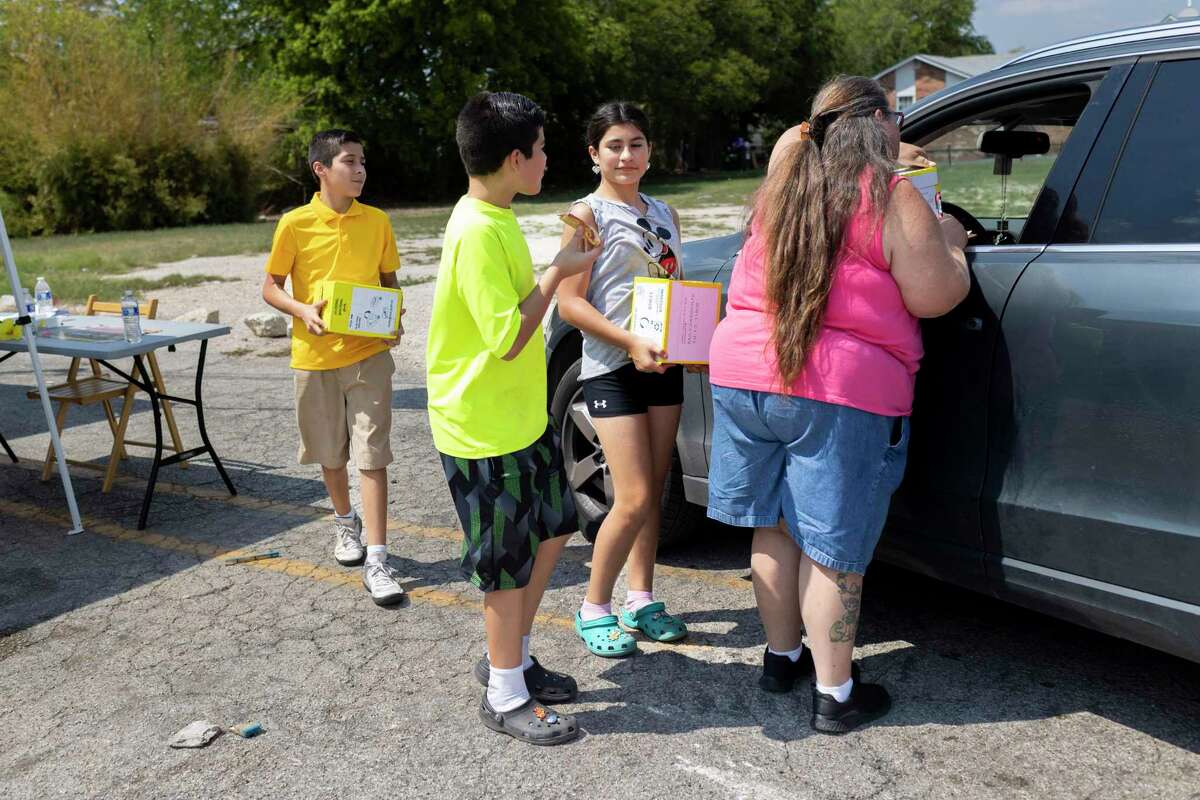 Siblings Jose Soto, 12, Jaelyssa “Chilli” Soto, 12, and Jayden Soto, 13, help to bring boxes of mayo to a car that pulled up to a food distribution as Mary Boubel talks with the driver at Treasures of Eldorado Thrift in San Antonio, TX, on Sept. 13, 2022.