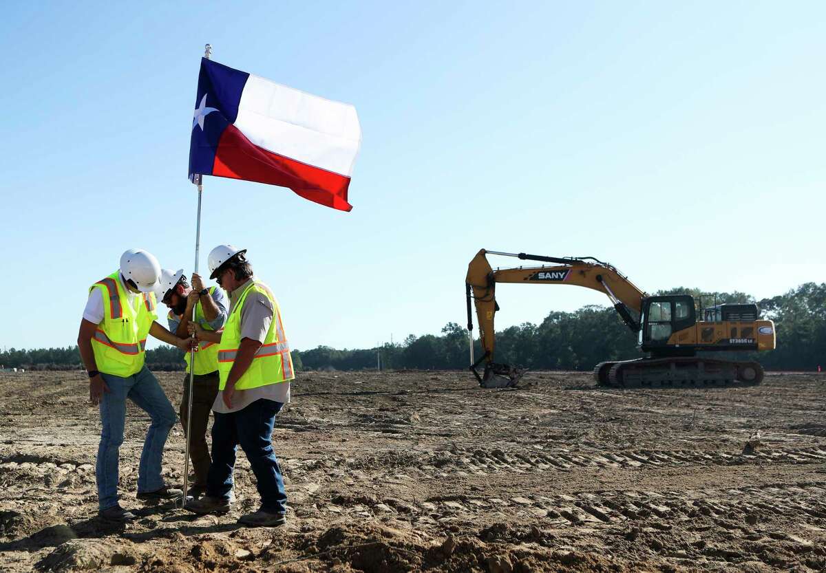 Workers install a Texas flag near the groundbreaking of the new 1.2 million-square-foot Northport Logistics Center in Conroe Park North, Wednesday, Sept. 14, 2022, in Conroe. Once completed, the completed will be the largest in the city’s industrial park to date.
