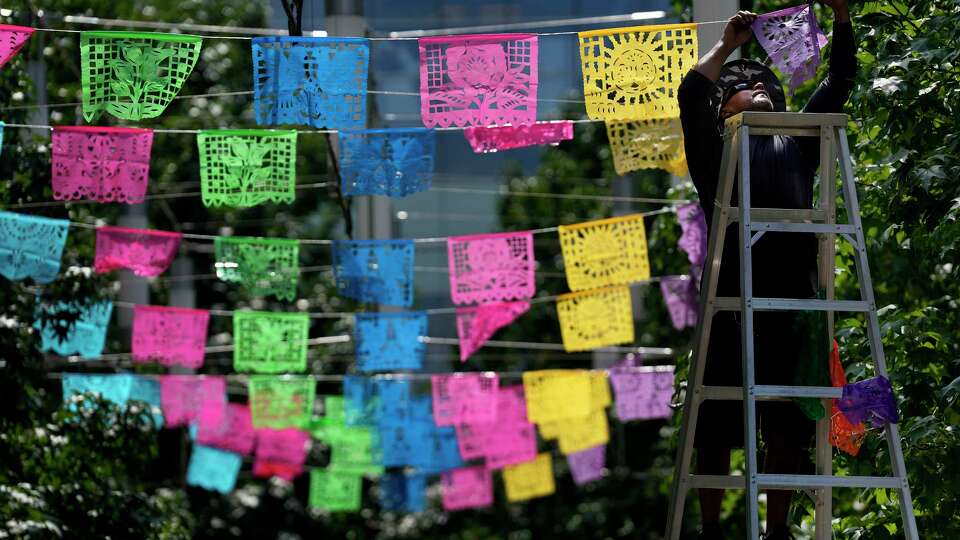 Tony Cervantes, installs colorful plastic papel picado in preparation for the Hispanic Heritage Month events in front of the George R. Brown Convention Center, Thursday, Sept. 15, 2022, in Houston.