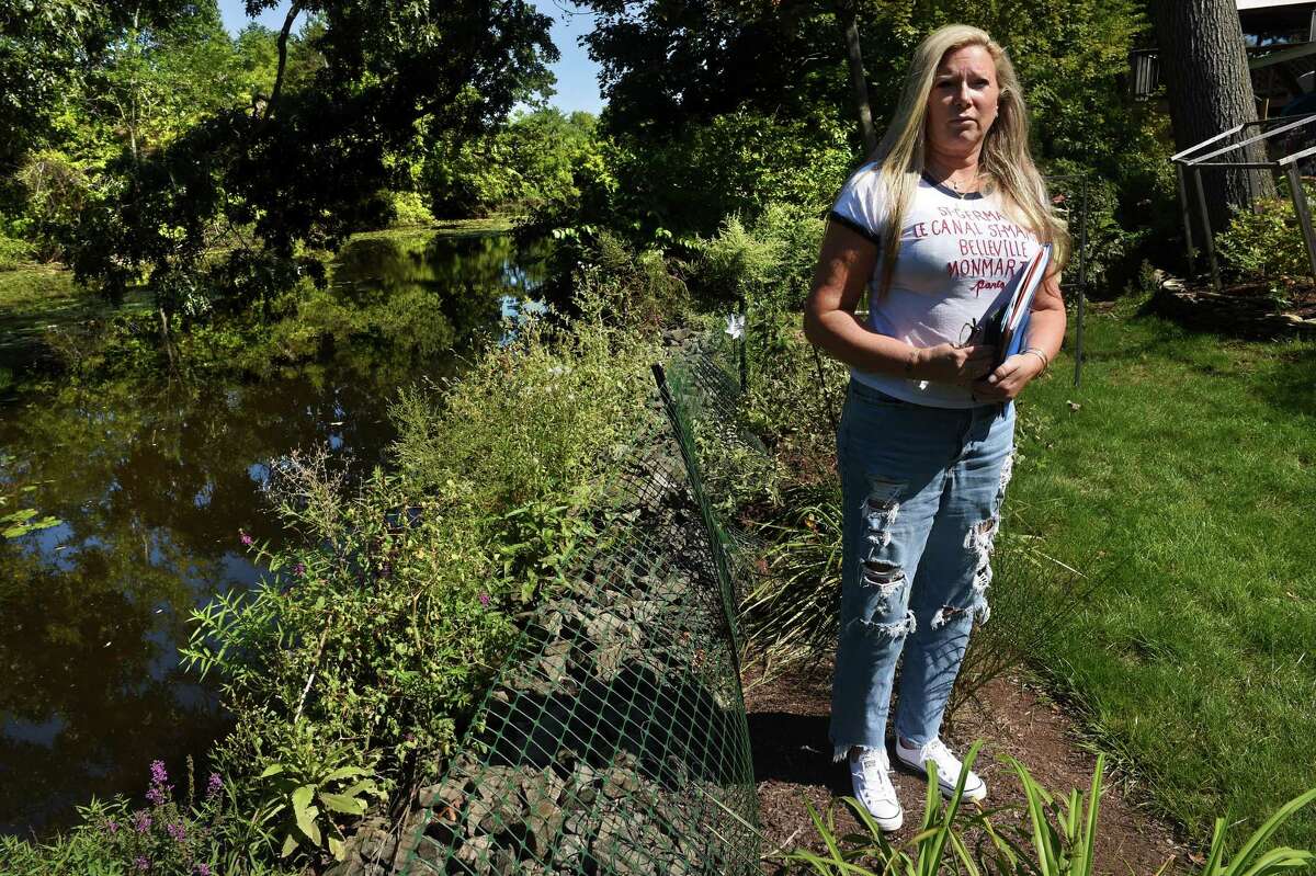 Lissa McCarthy is photographed at the back edge of her property on Lake Avenue that borders Upper Lake Phipps in West Haven on September 15, 2022.