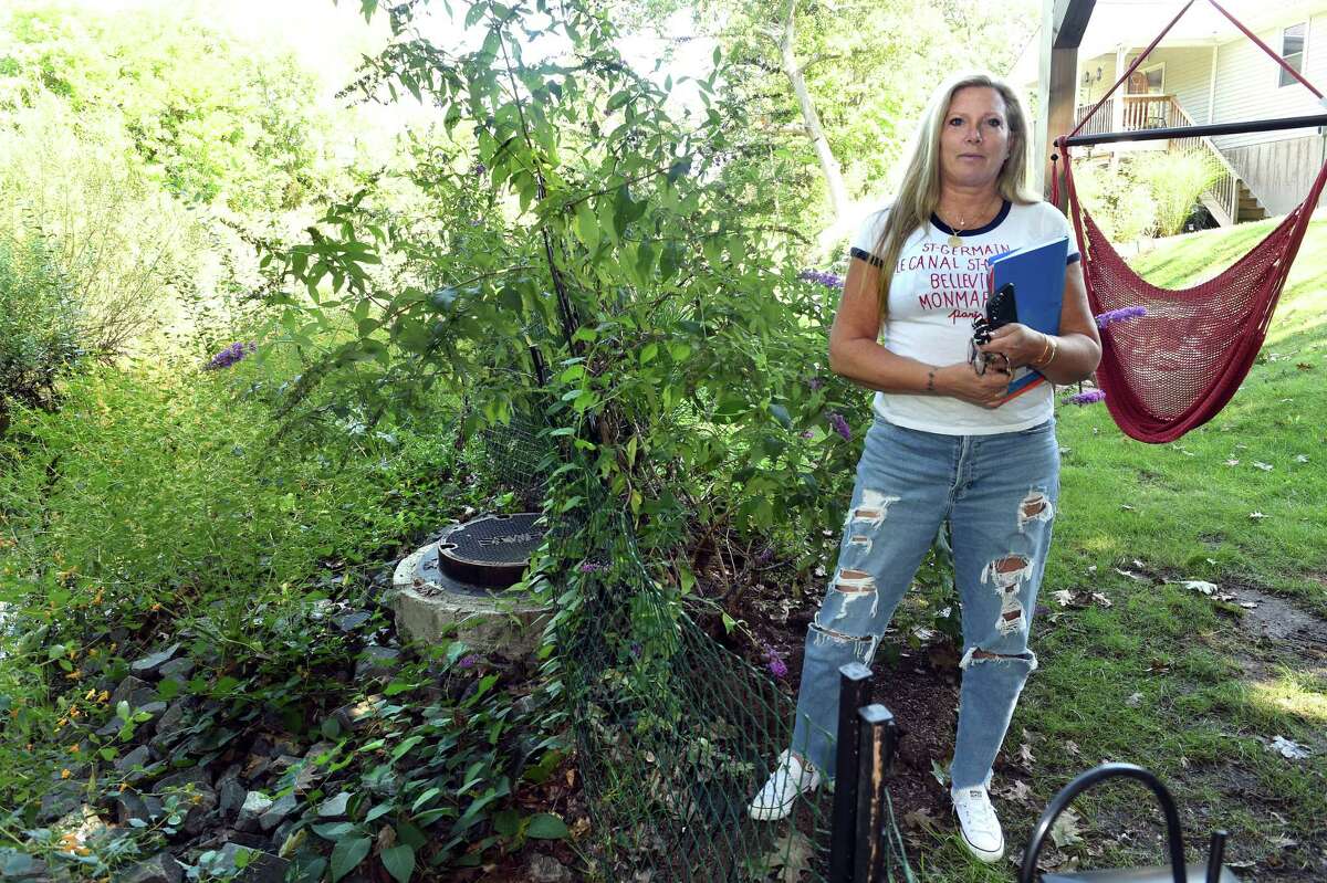 Lissa McCarthy is photographed next to a sewer line at the back edge of her property on Lake Avenue that borders Upper Lake Phipps in West Haven on September 15, 2022.