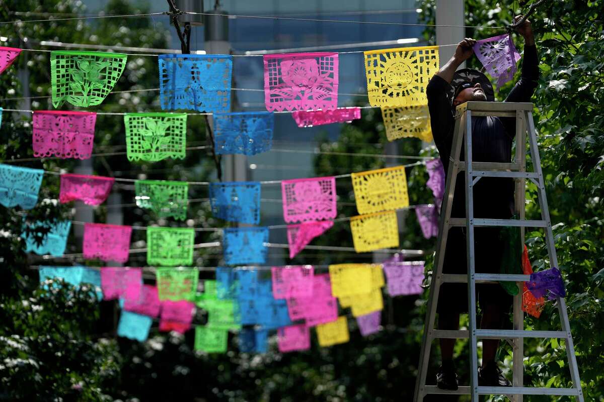 Tony Cervantes, installs colorful plastic papel picado in preparation for the Hispanic Heritage Month events in front of the George R. Brown Convention Center, Thursday, Sept. 15, 2022, in Houston.