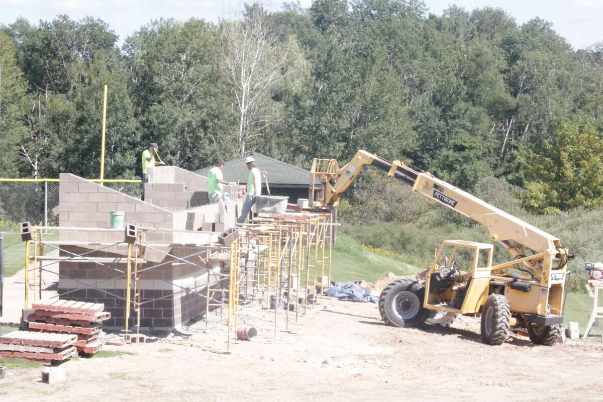 Construction employees work on the new softball dugouts at the Big Rapids varsity diamond.