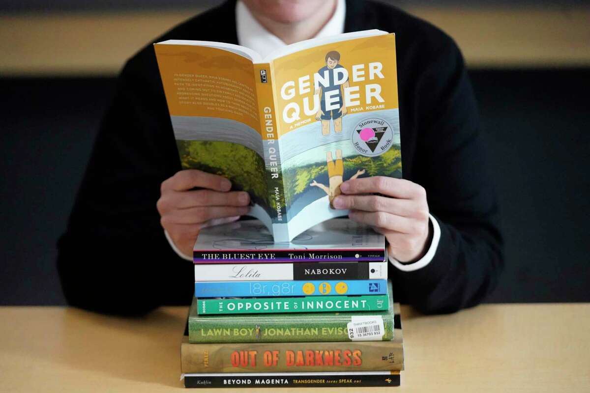 FILE - Amanda Darrow, director of youth, family and education programs at the Utah Pride Center, poses with books that have been the subject of complaints from parents in Salt Lake City on Dec. 16, 2021. The wave of attempted book banning and restrictions continues to intensify, the American Library Association reported Friday. Numbers for 2022 already approach last year's totals, which were the highest in decades. (AP Photo/Rick Bowmer, File)