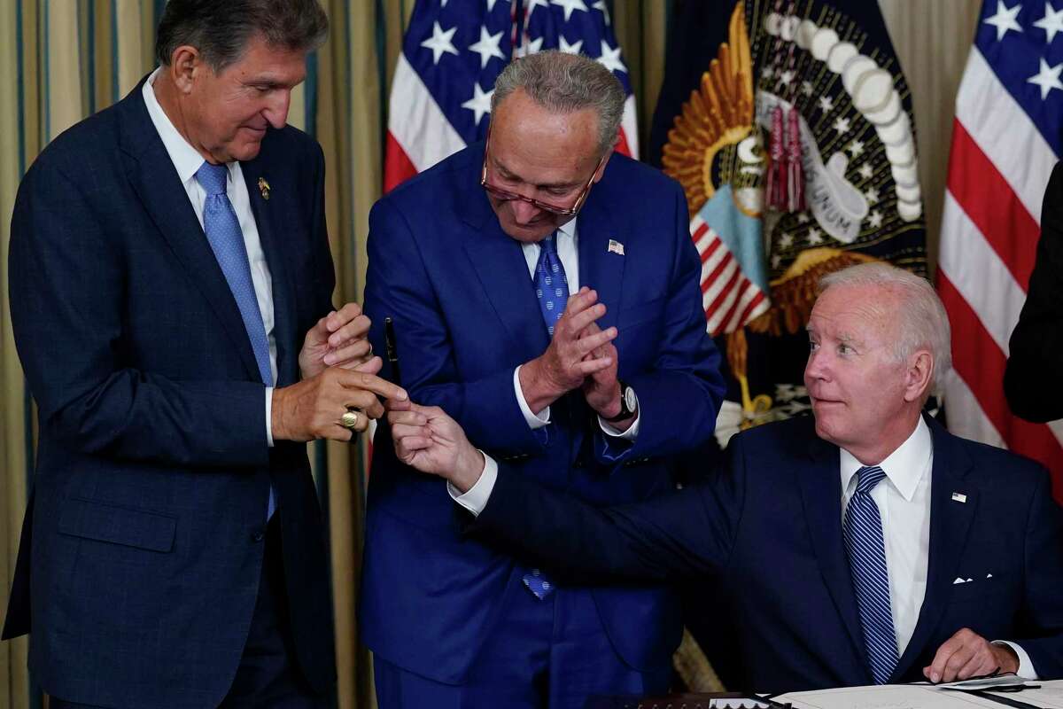 President Joe Biden hands the pen he used to sign the Democrats' landmark climate change and health care bill to Sen. Joe Manchin, D-W.Va., as Senate Majority Leader Chuck Schumer of N.Y., watches in the State Dining Room of the White House in Washington, Aug. 16, 2022. Manchin made a deal with Democratic leaders as part of his vote pushing the party's highest legislative priority across the finish line last month. Now, he's ready to collect. But many environmental advocacy groups and lawmakers are balking.