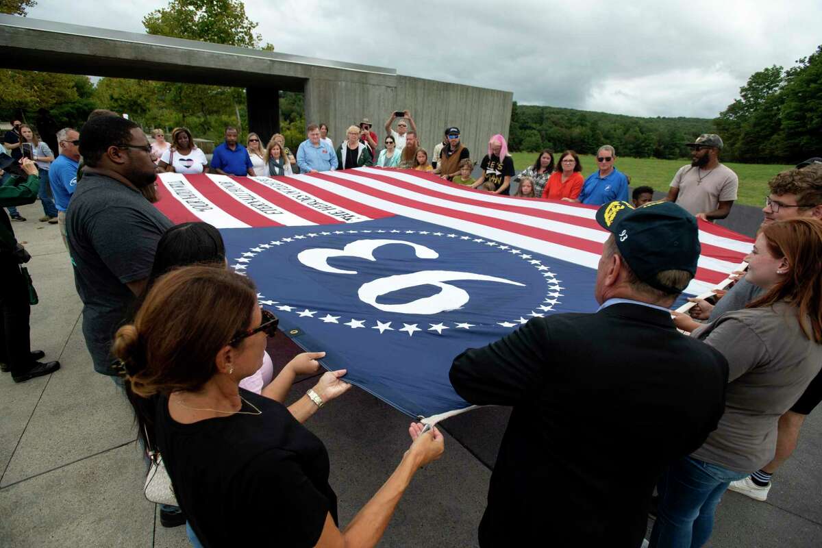 Visitors to the Flight 93 National Memorial participate in a memorial service by opening the Flight 93 Heroes flag on the 21st anniversary of the Sept. 11, 2001, terrorist attacks in Shanksville, Pa.