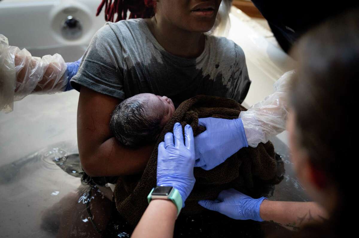 Midwives hand a new mom her baby to hold for the first time at a birthing center in Argyle, Texas, on June 26, 2022.