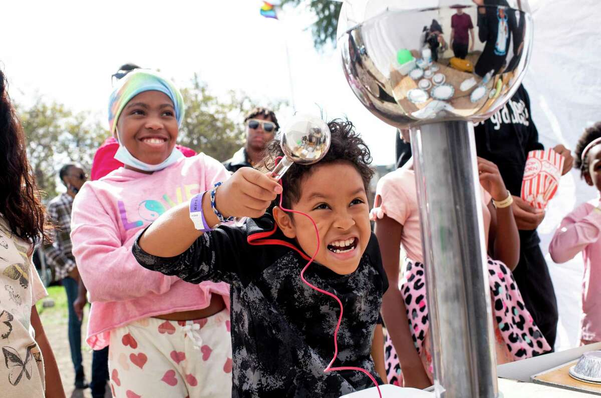 Salahuddin S., 9, of Oakland makes a face at his reflection while he plays with a Van de Graaff generator during the second annual Kits Cubed STEM Fair at Oakland Technical High School.