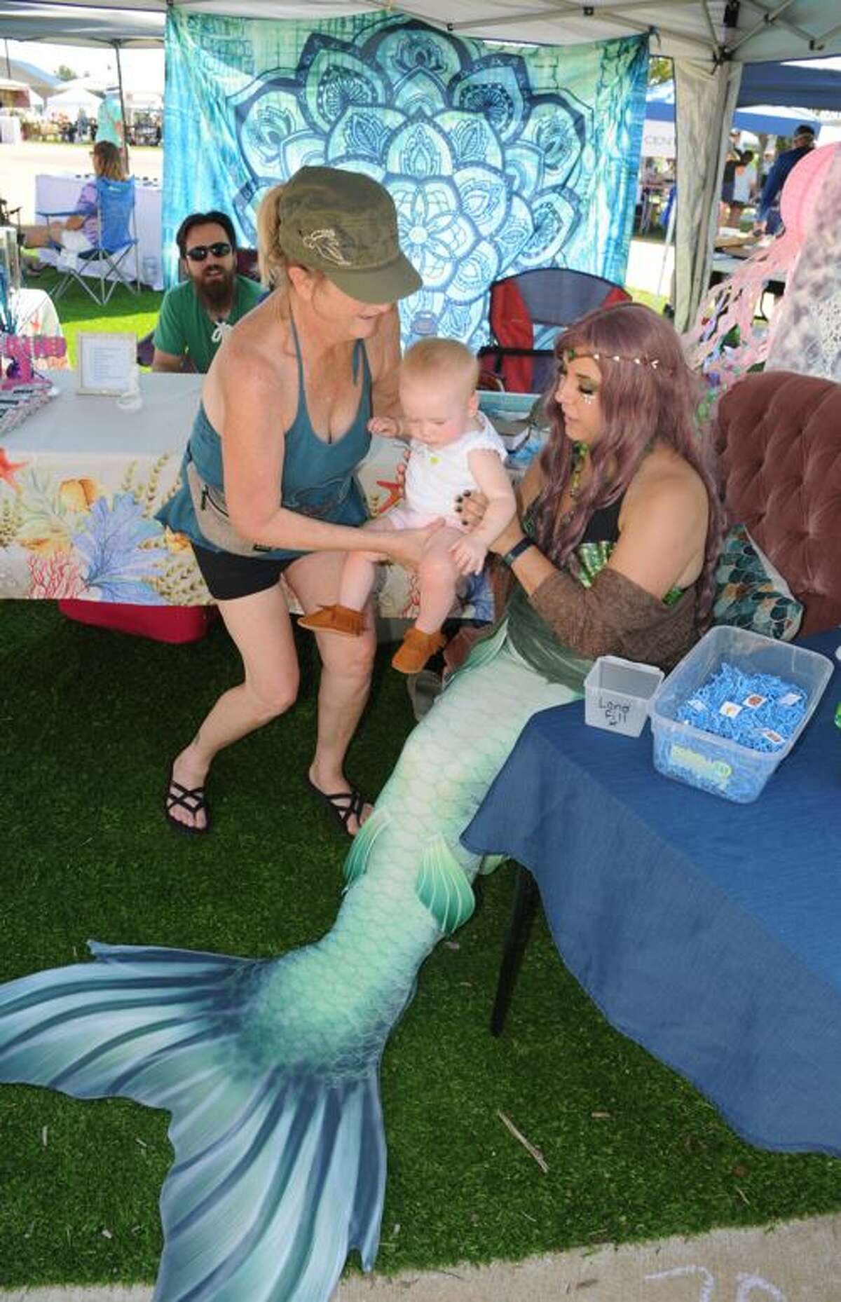Rachel Schuyler hands her granddaughter, Nora Mae, to Mermaid Diamond for a photo during Saturday's Mississippi Earthtones Festival on the Alton riverfront.