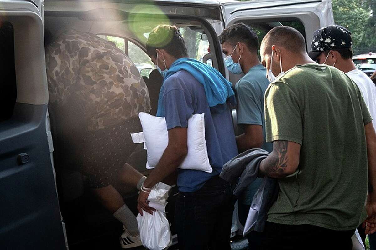 Migrants from Venezuela, who boarded a bus in Texas, wait to be transported to a local church by volunteers after being dropped off outside the residence of Vice President Kamala Harris at the Naval Observatory in Washington.