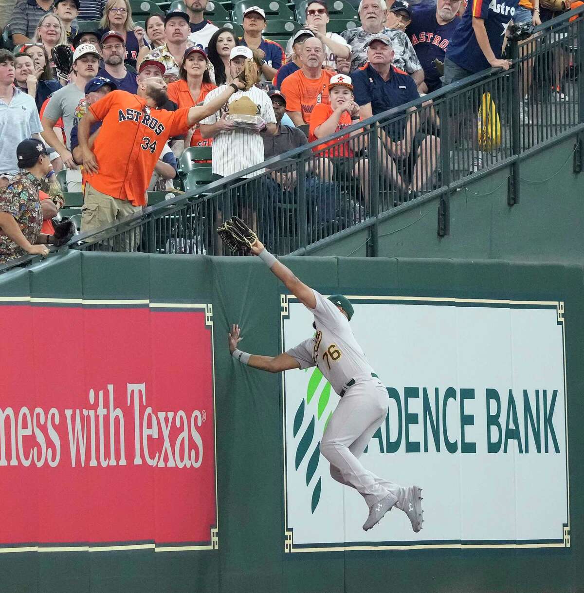 Oakland Athletics first baseman Dermis Garcia (76) jumps up against the left field wall as a fan reached out to catch Houston Astros Yordan Alvarez’s fly out on the fan interference during the first inning of an MLB baseball game at Minute Maid Park on Sunday, Sept. 18, 2022 in Houston.